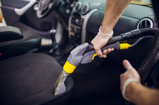 Intérieur de véhicule automobile, personne utilisant un aspirateur professionnel pour nettoyer la sellerie